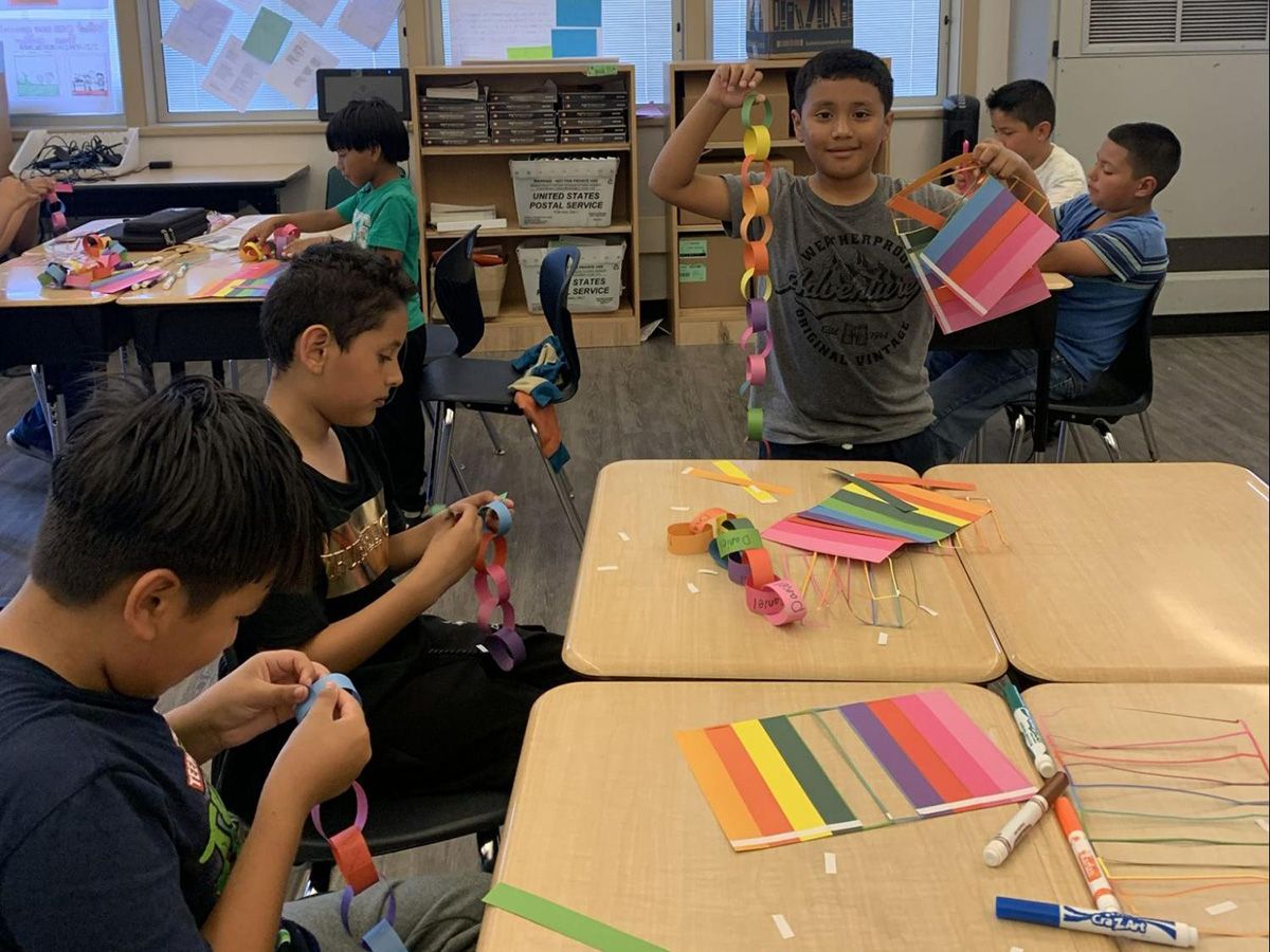 elementary school age boys working on an art project with colored paper